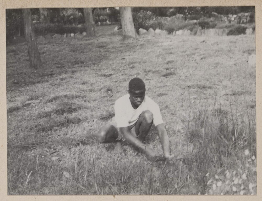 [Man kneeling in field]
