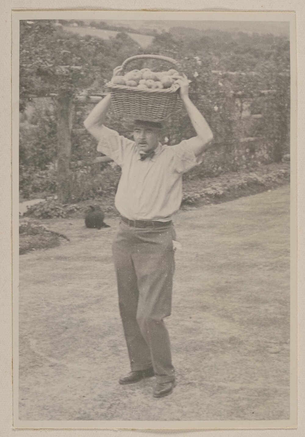 [Man carrying basket of fruit on his head]