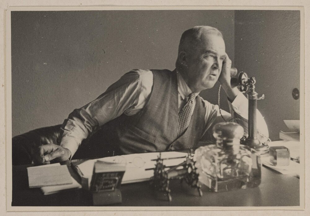 [Man at sitting at desk using telephone]