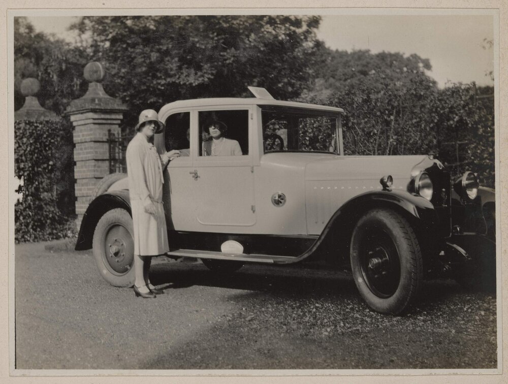 [Woman posing in front of motor car]