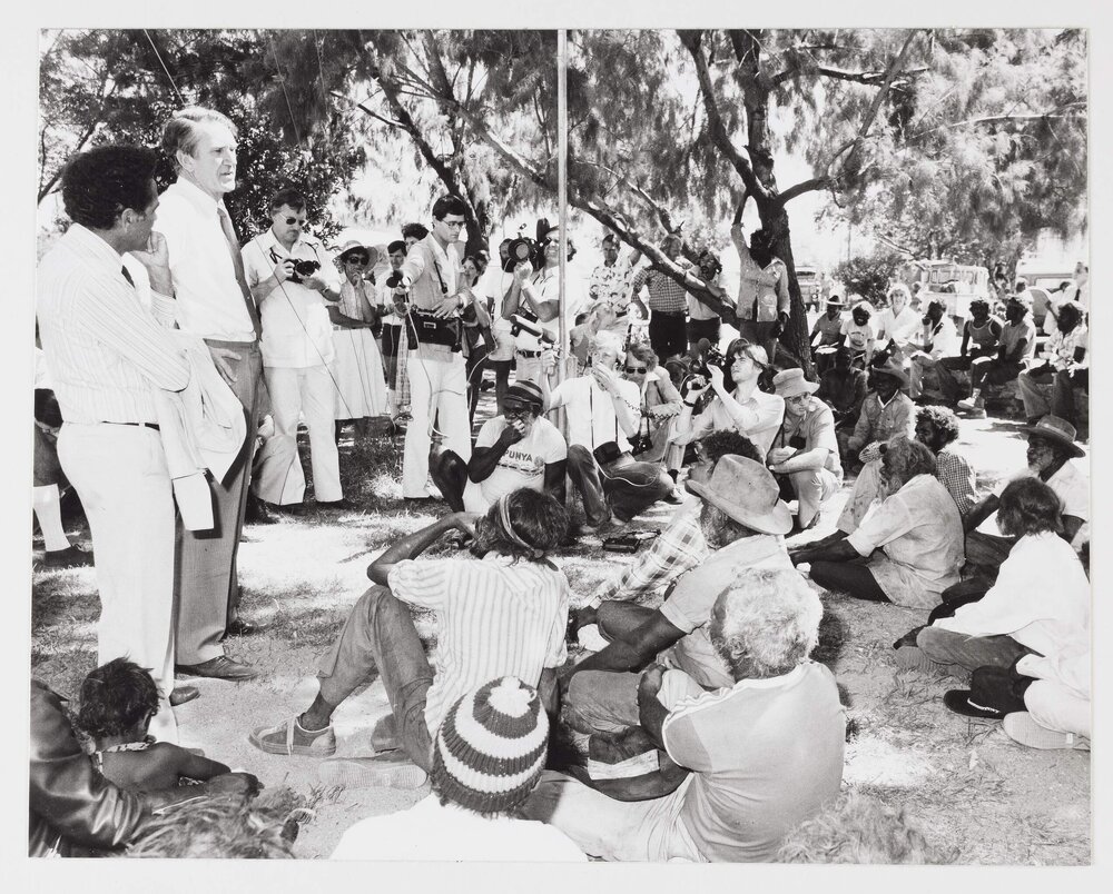 [Malcolm Fraser, watched by journalists, speaking to a group of Aboriginal Australians during a visit to the Northern Territory]