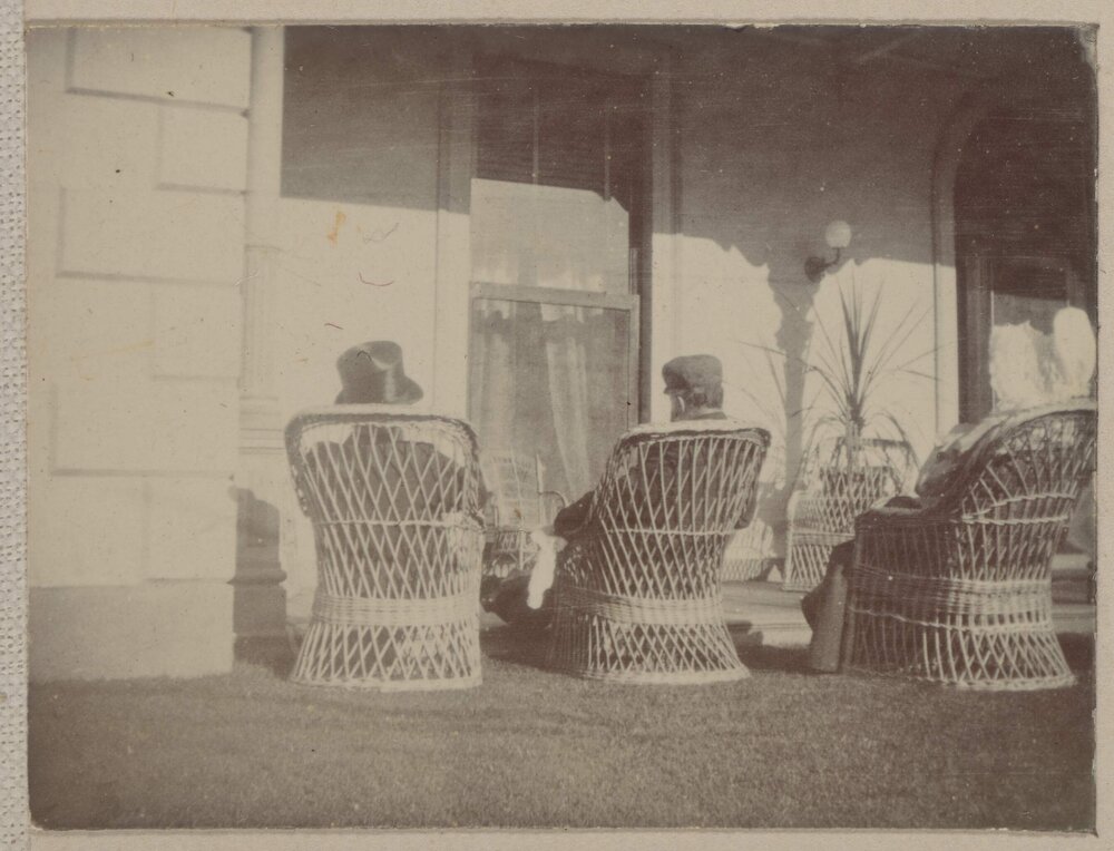 [Two men sitting in cane chairs]