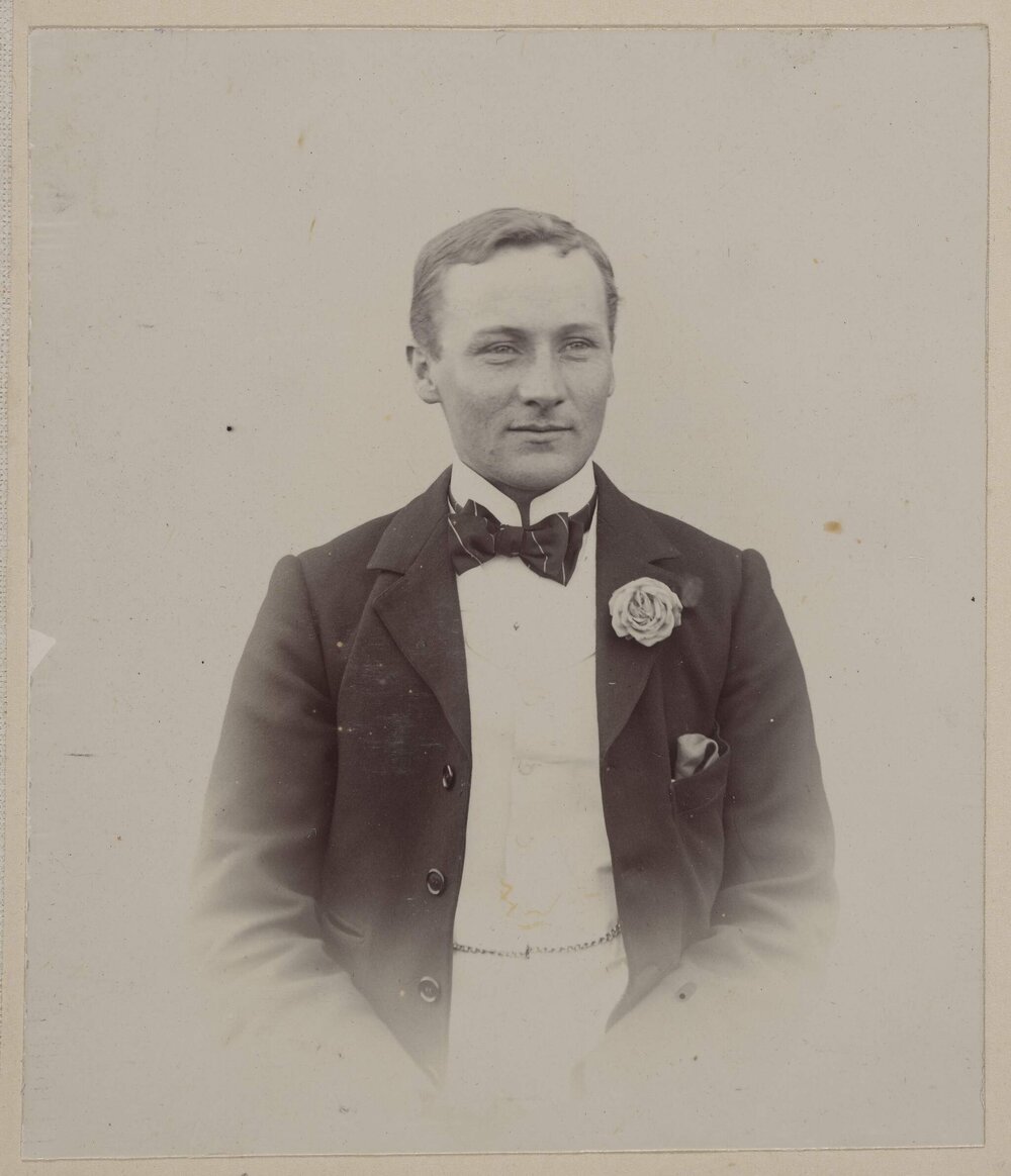 [Man wearing bowtie with flower in jacket lapel]