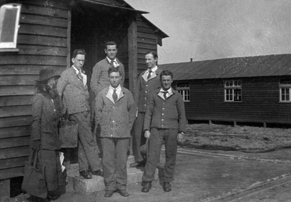 Five men and a woman at the dooway of timber building