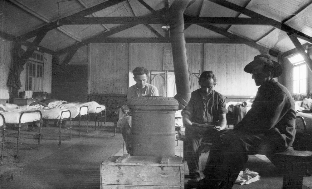 Three men sitting around a stove heater