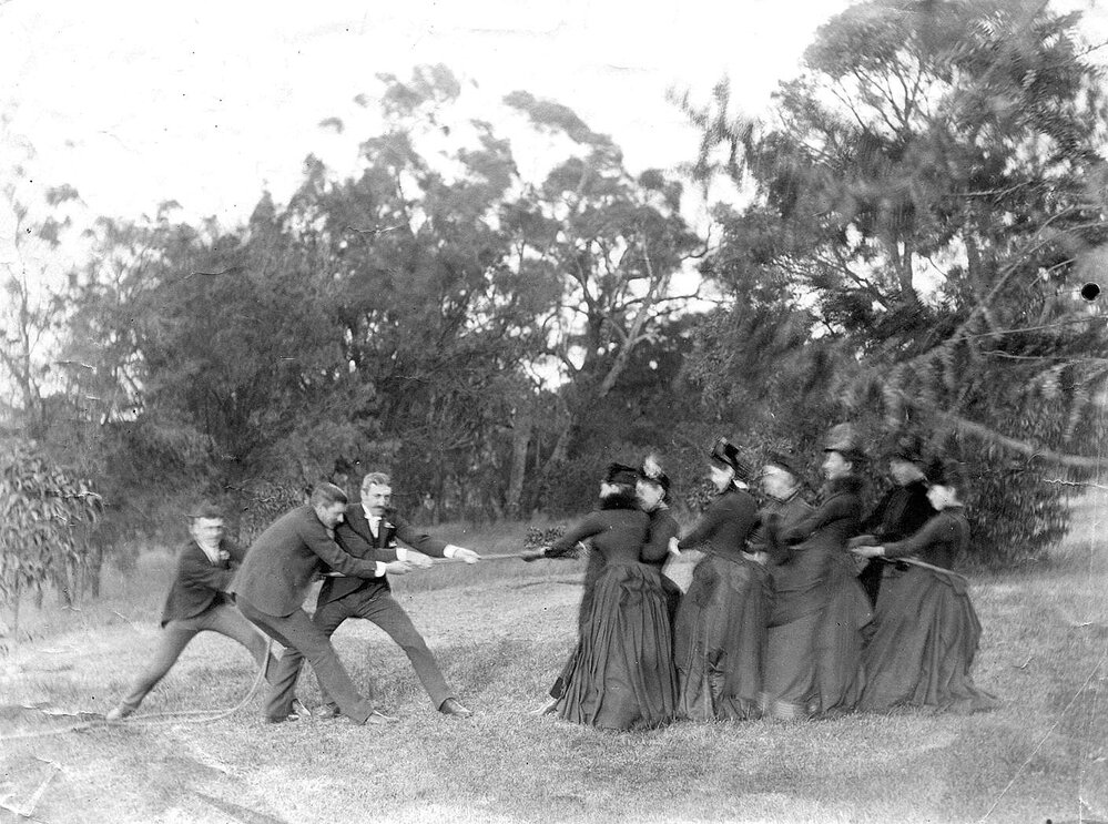 Group of men and women playing "tug of war"