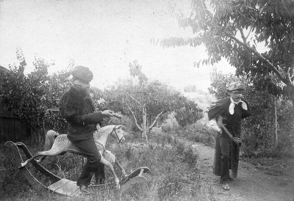 Photo of two children playing outdoors, one on rocking horse