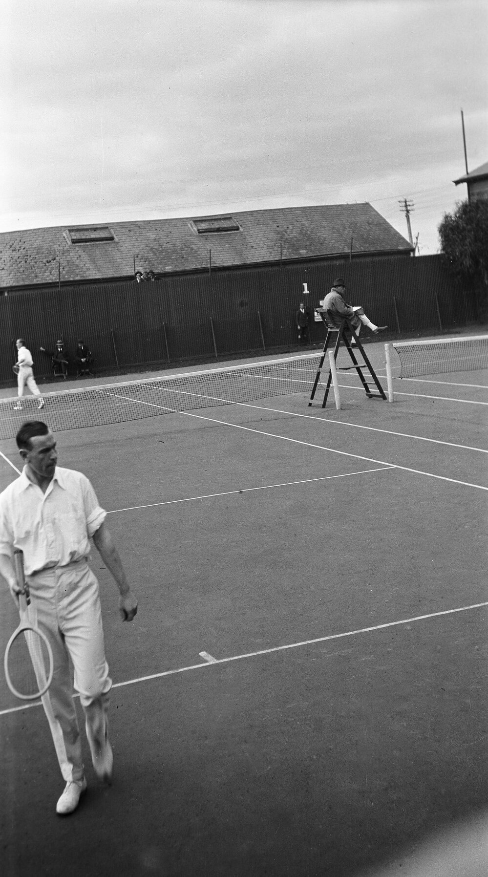 Tennis courts with men playing a singles game