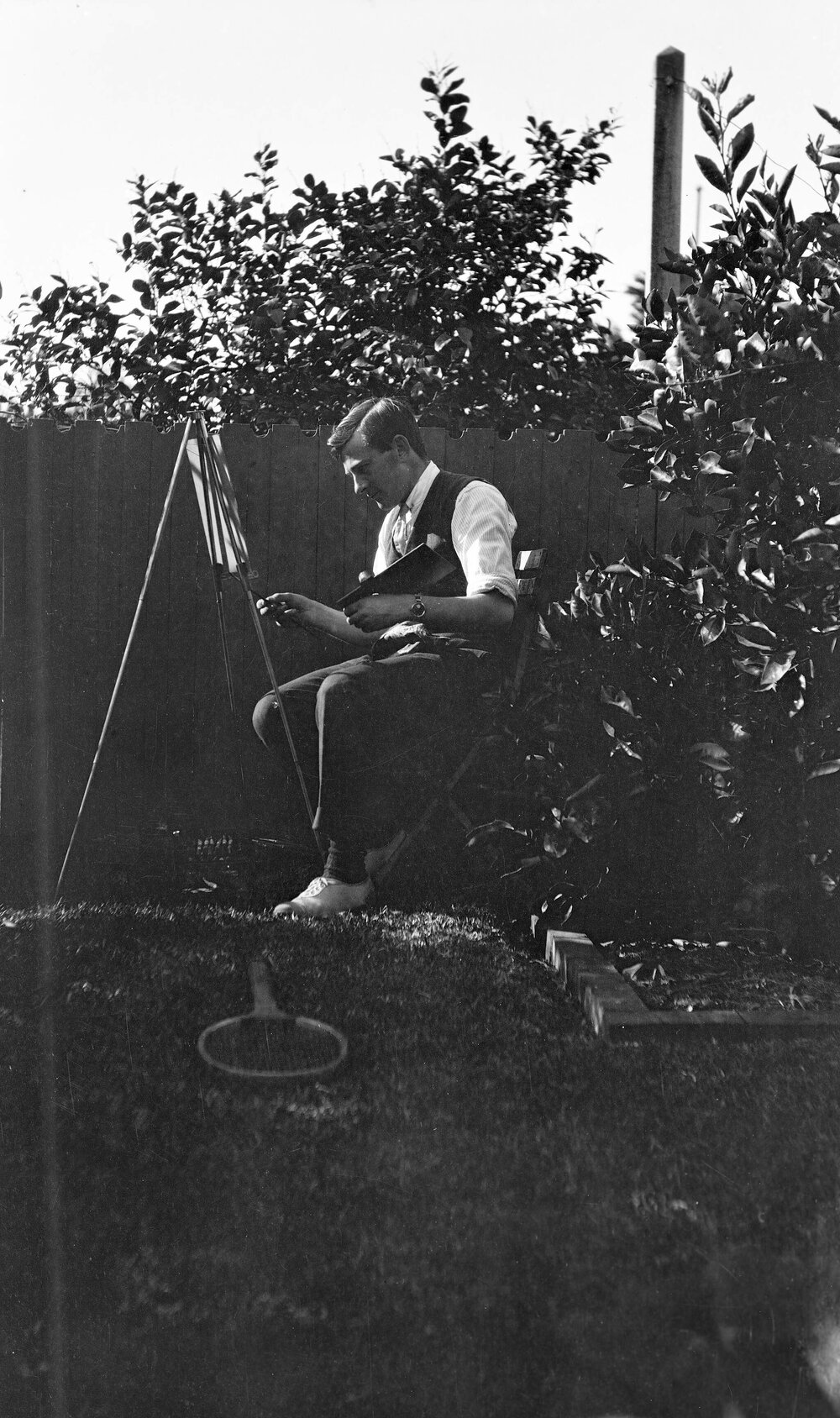 Man sitting painting at an easel in a garden