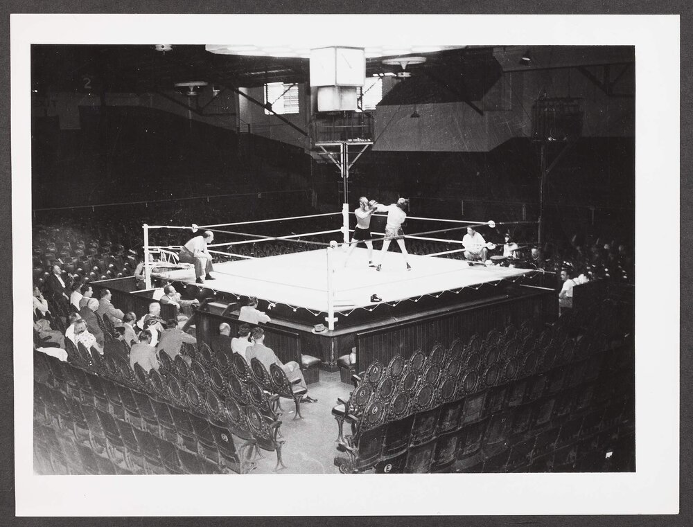 [Photograph of a boxing match taking place inside a ring]
