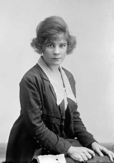 Studio portrait of a woman wearing a check blouse and dark jacket.