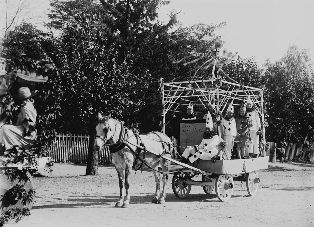 An open car decorated with flags and carrying girls dressed as fairies.