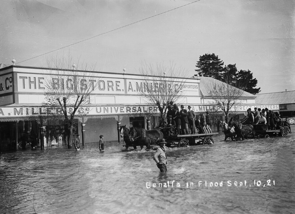 Horse drawn drays loaded with people moving through floodwaters in central Benalla, on 10th September 1921.