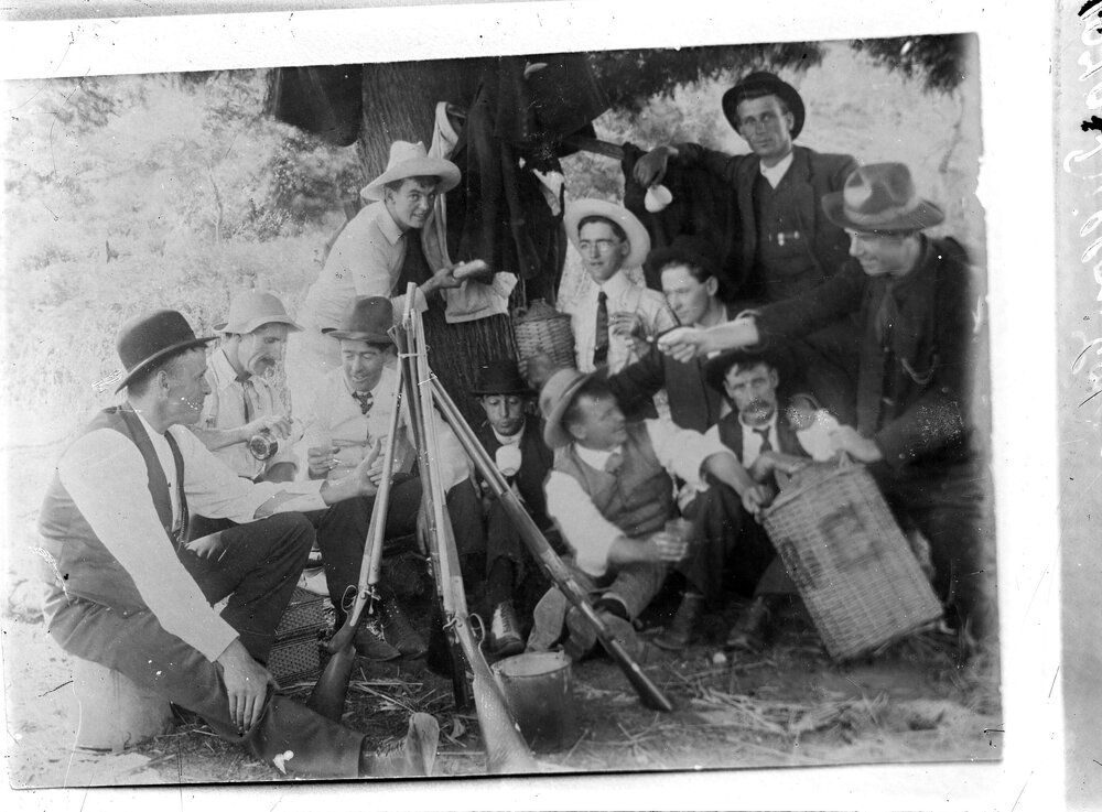A group of unidentified young men relaxing and drinking under a tree.