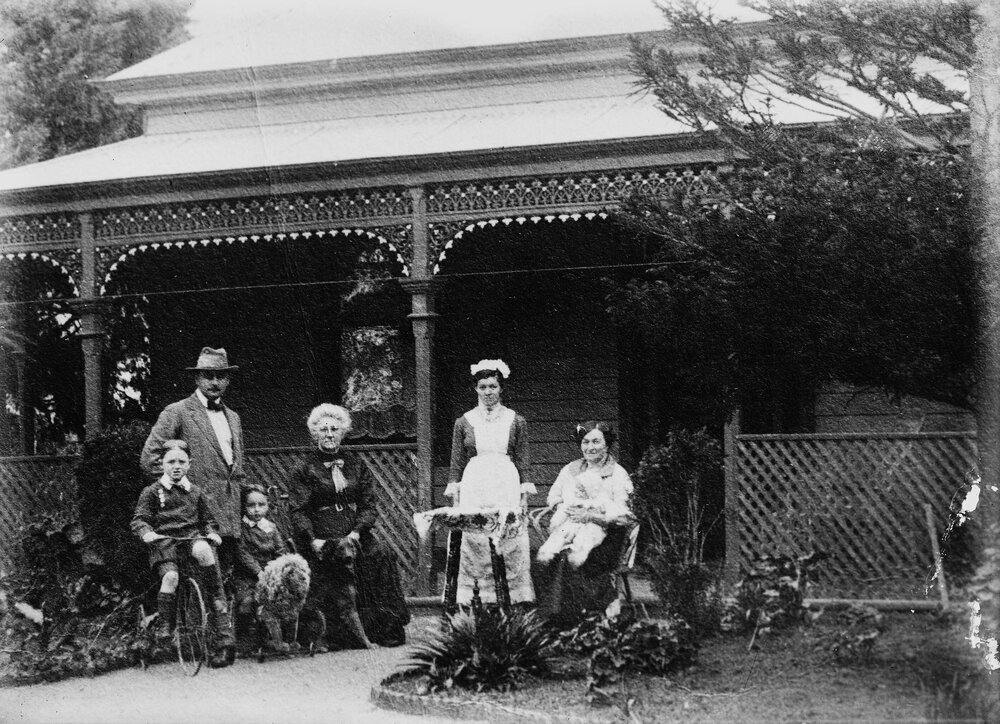 An  unidentified group of people in front of a verandahed timber residence.