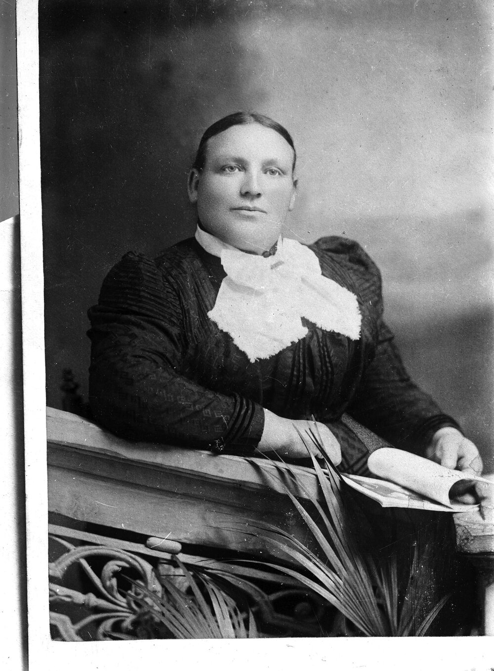 A large unidentified woman leaning on a balustrade.