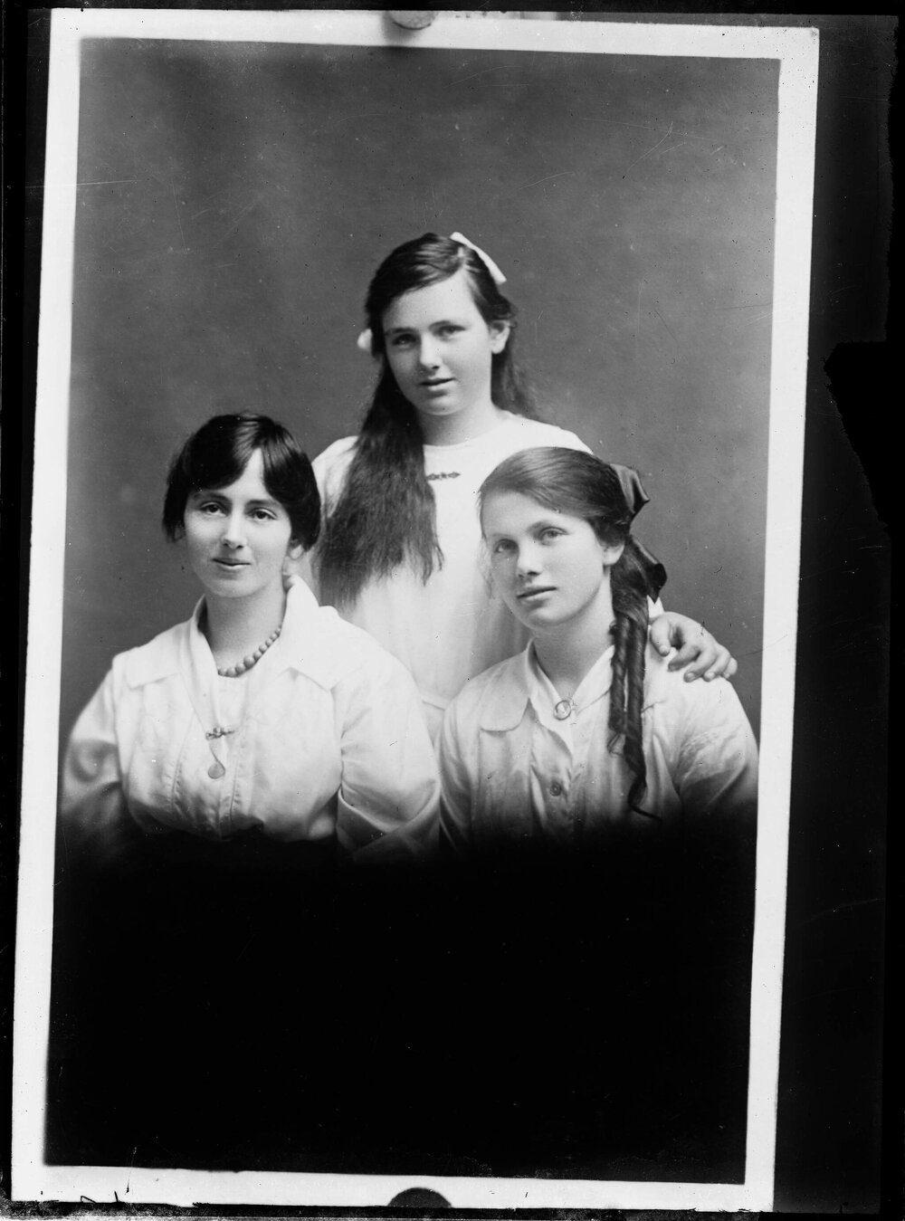Studio portrait of three unidentified young women dressed in white.