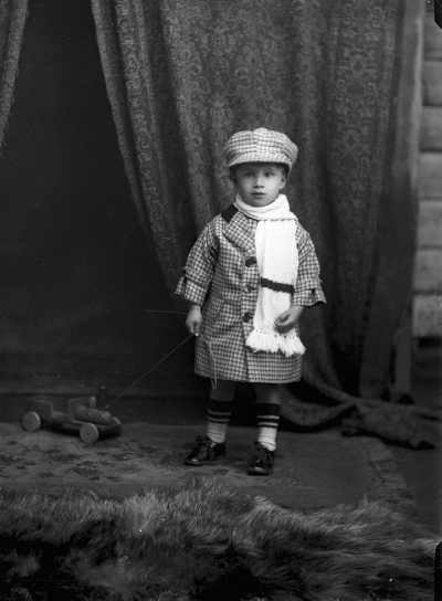 Studio portrait of a young Master Bell dressed in a hat and coat.