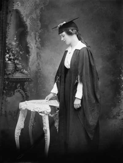 Studio portrait of Miss M. Cailin wearing an academic gown.