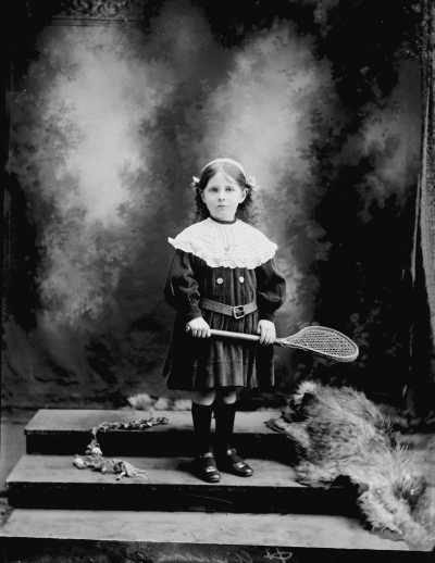 Studio portrait of young girl holding a racquet..