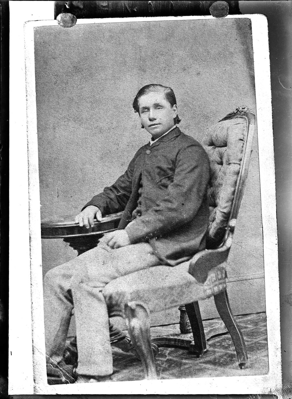 Portrait of an unidentified young man seated at a round table.