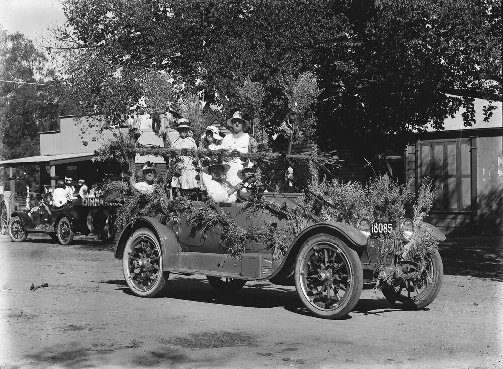 A car decorated with wheat and carrying several women.