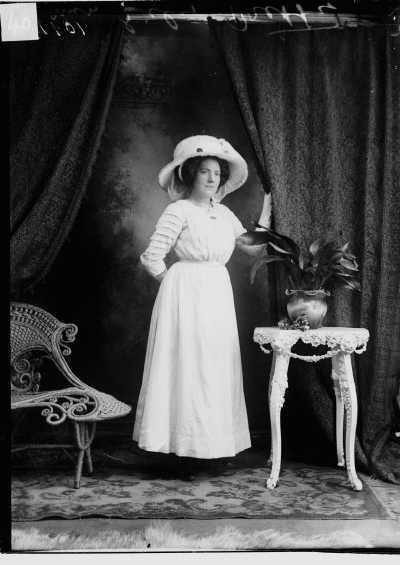 Studio portrait of Miss Lily Pretty wearing a large hat.