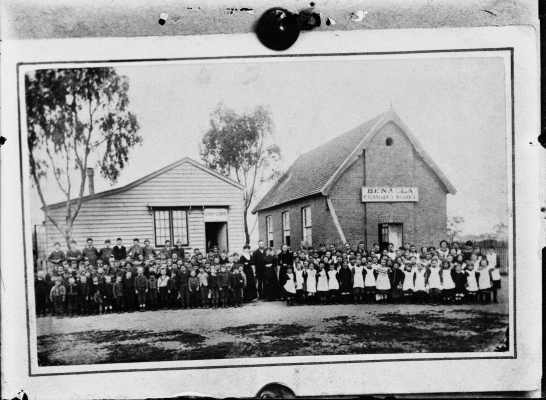 Pupils and teachers grouped outside two Benalla school buildings.