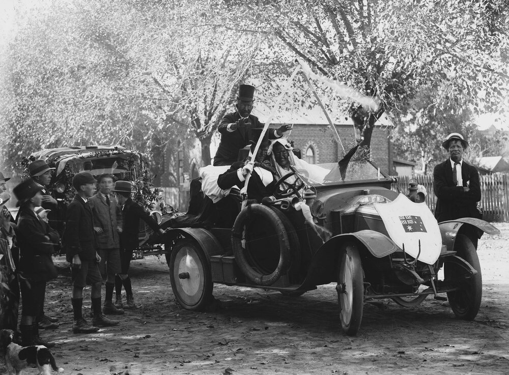 An open car carrying people in costume, possibly dressed as minstrels.