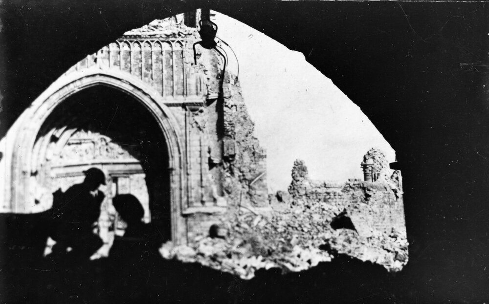 Soldiers silhouetted in front of a damaged building.