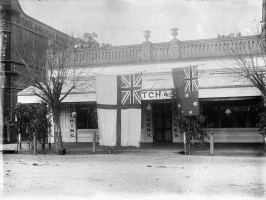 Flags displayed for peace celebrations in front of a drapery shop in Benalla.