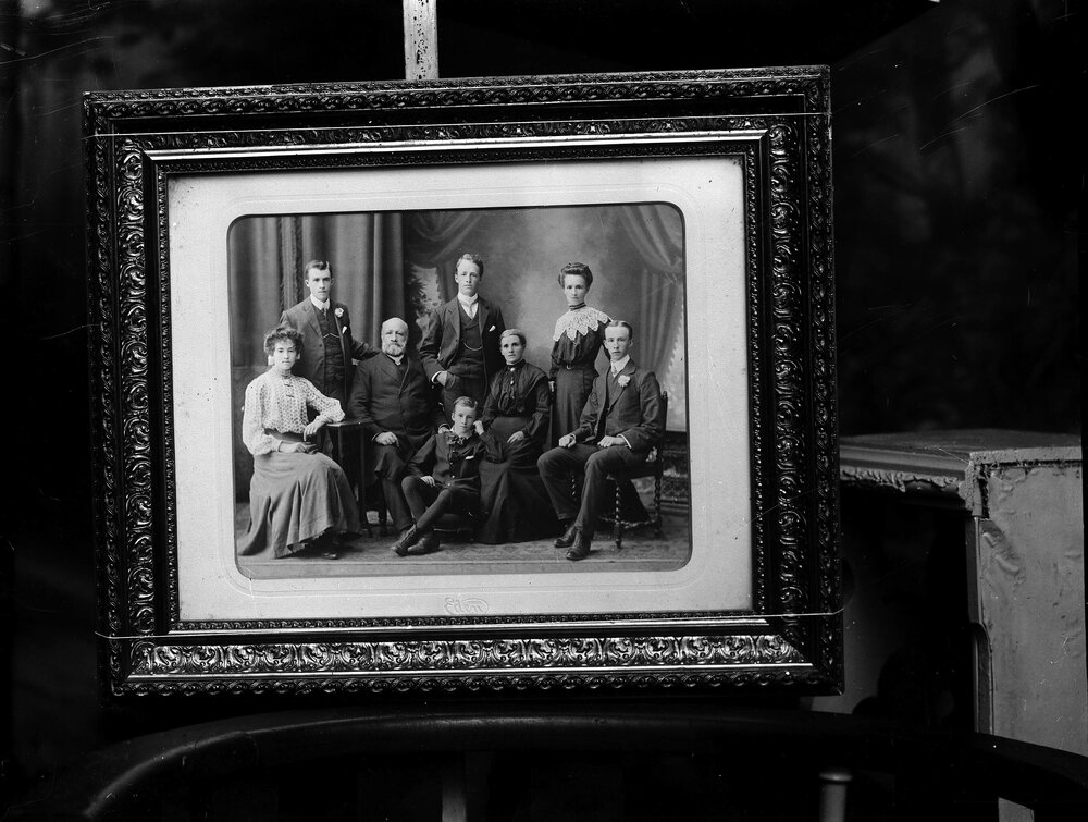 A posed group of eight unidentified people in a studio.