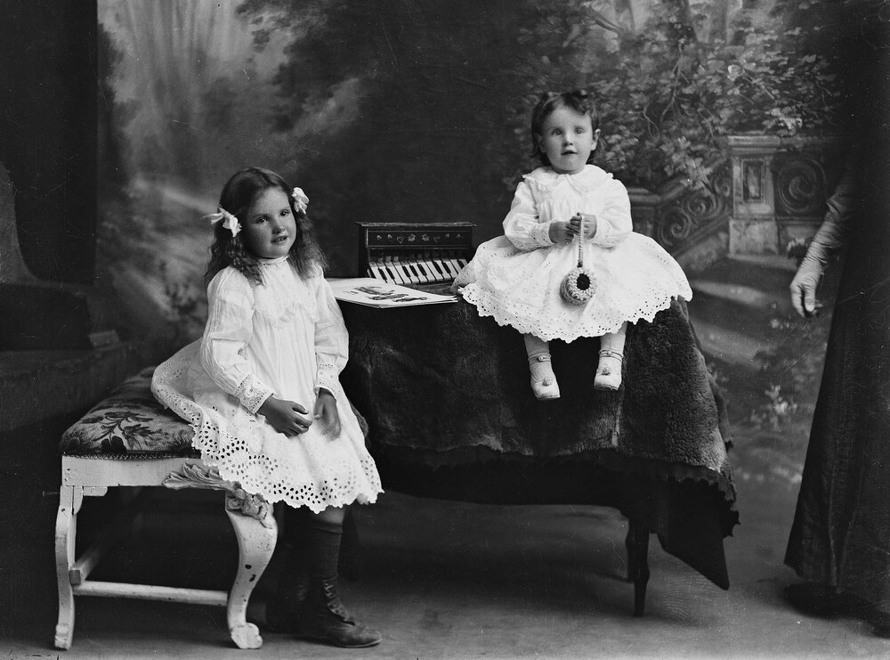 Portrait of two young girls seated in a studio.  Family name Wallace.