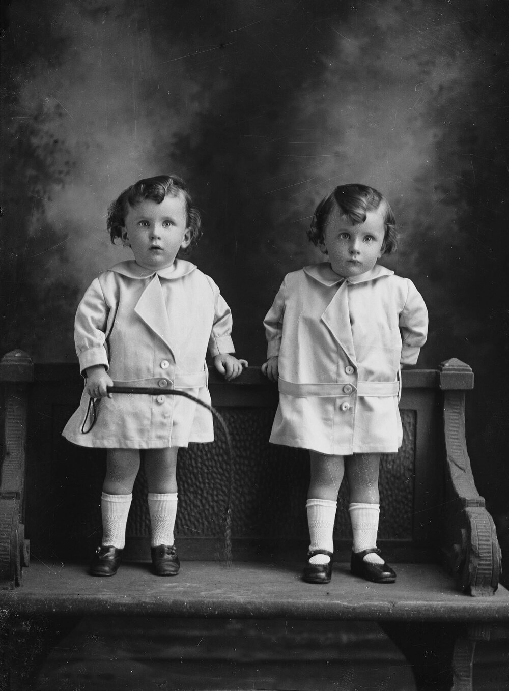 Studio portrait of two young girls standing on a bench.  Family name Keaney or Reaney.