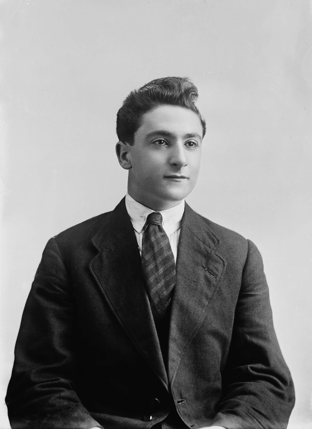Studio portrait of a young man in a suit and wide striped tie.