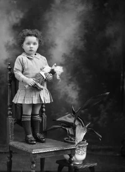 Studio portrait of a young girl standing on a chair.  Family name Peterson.
