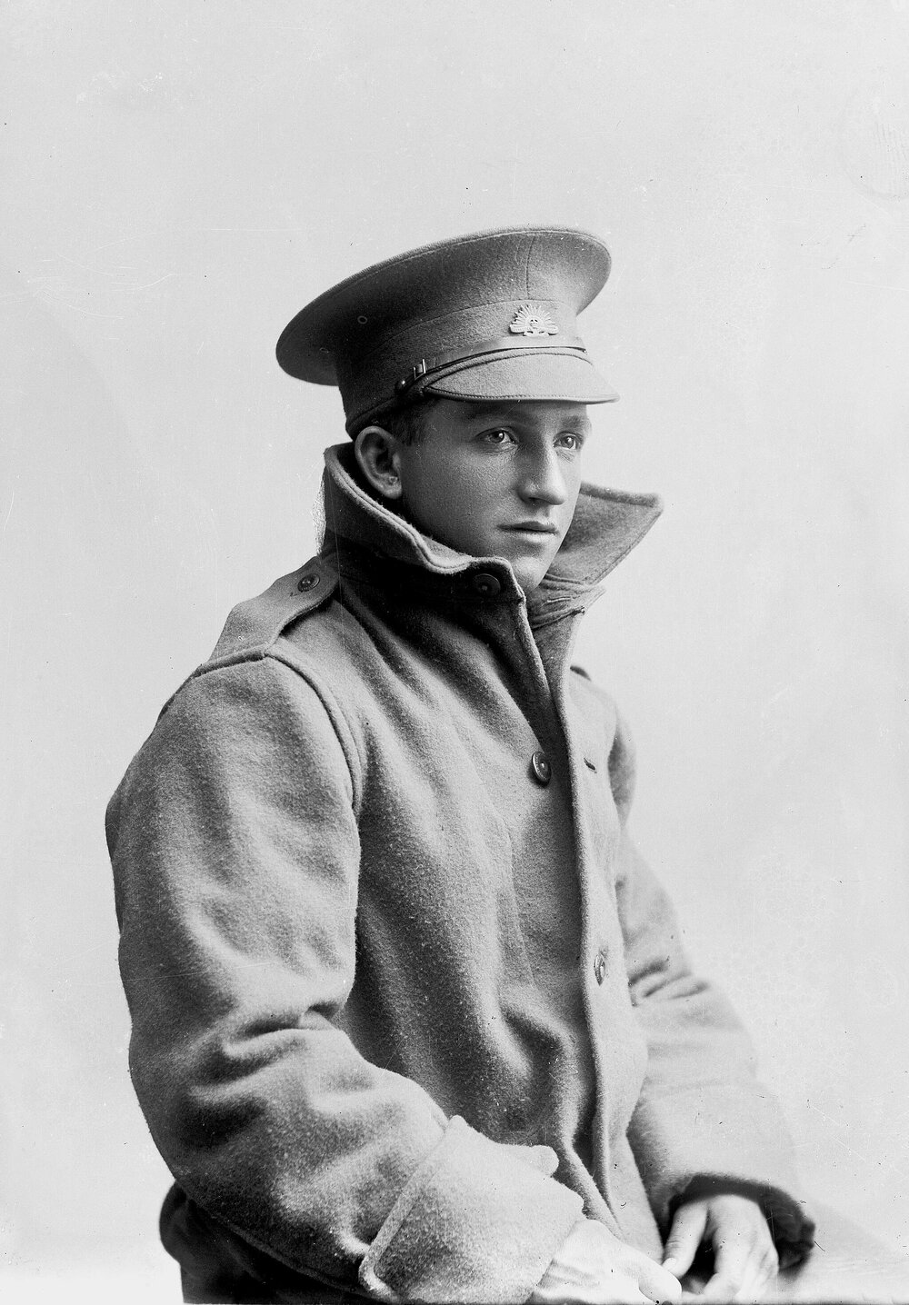 Studio portrait of a young man wearing a great coat and Australian Army cap.
