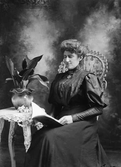 Studio portrait of a seated woman with a book. Family name Mc Donald.
