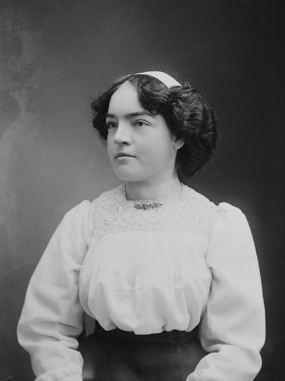 Studio portrait of a seated woman wearing a white blouse.