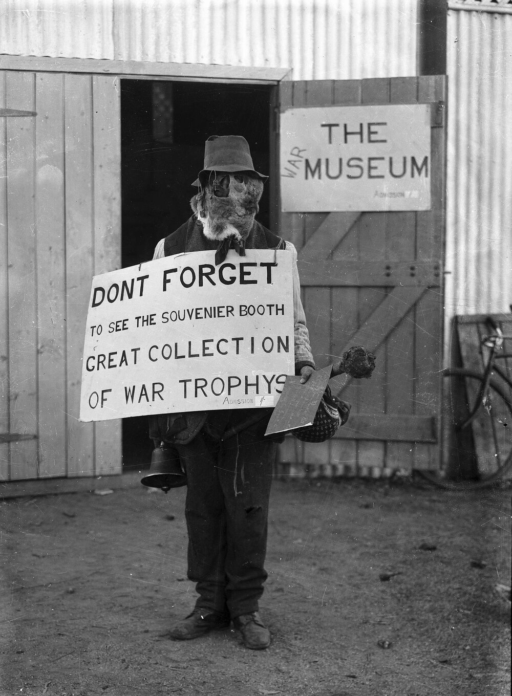 A man wearing an animial skin balaclava outside a war museum, possibly at Benalla, Victoria.