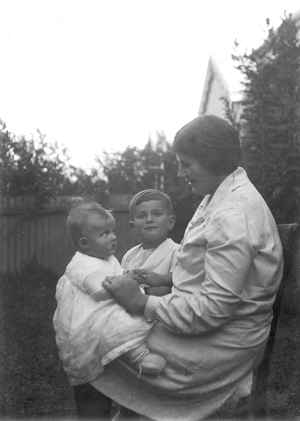 An informal outdoor portrait of a seated woman and two young children.