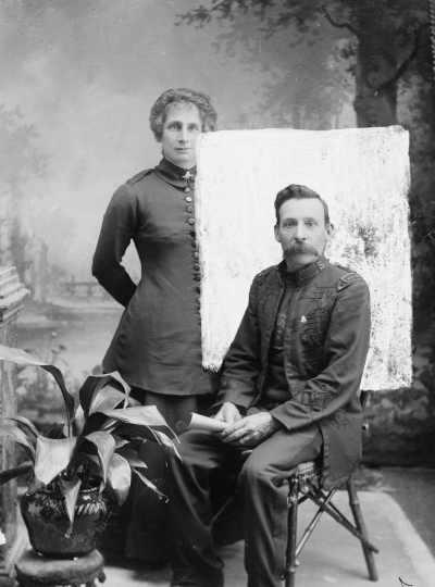 Studio portrait of a seated man and a standing woman.  Family name Leonard.