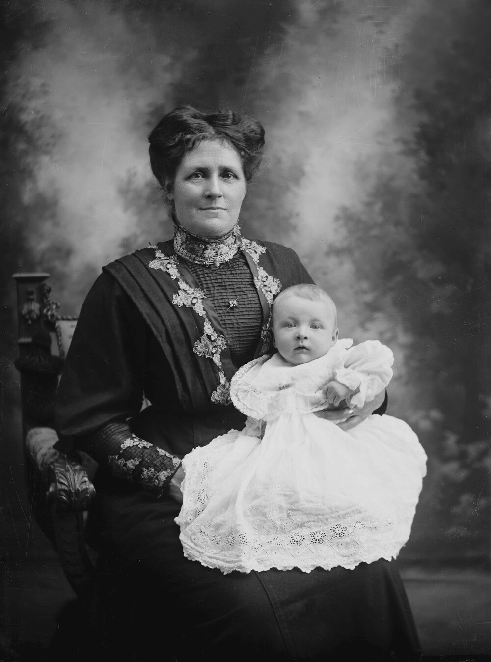 Studio portrait of a seated woman holding a baby.