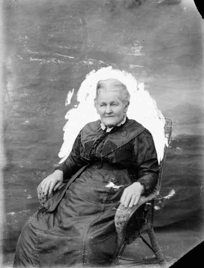 Portrait of an unidentified elderly lady seated in a wicker chair.