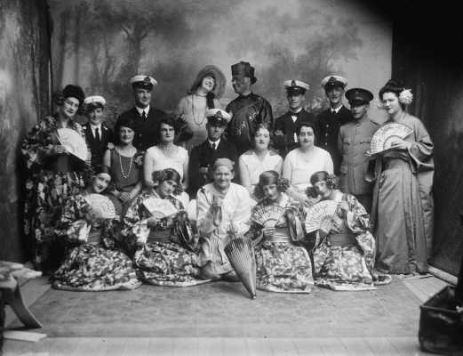 A theatrical group of men and women dressed in performance costume.