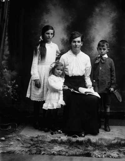 Studio portrait of a seated woman with three children.  Family name Earl.
