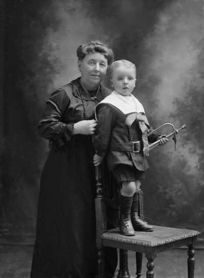 Studio portrait of a woman with a young boy who holds a bugle.