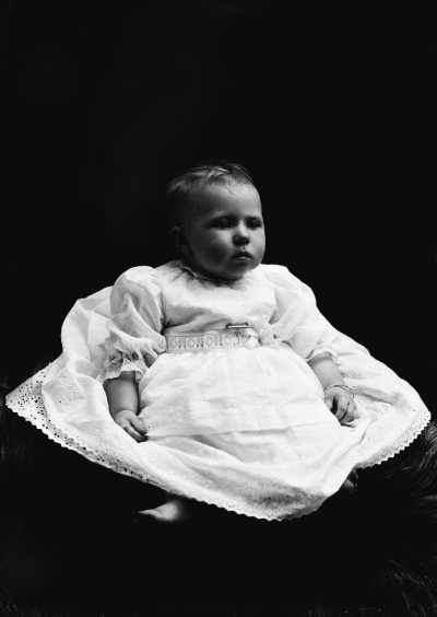Studio portrait of a baby wearing a dress.  Family name Hunt.