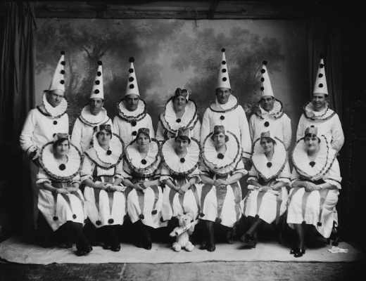 A posed group of men and women dressed in clown costumes.