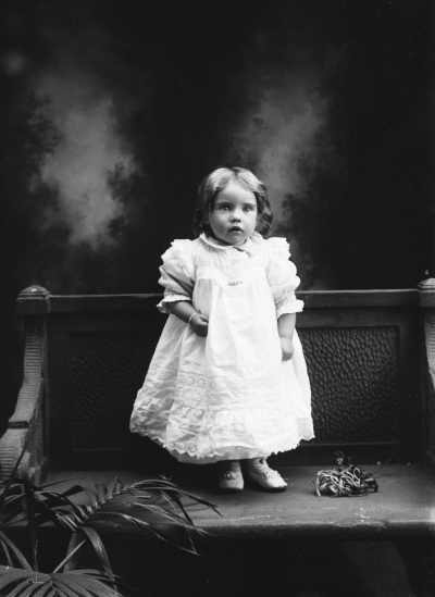 Studio full-length portrait of a young girl standing on a bench.